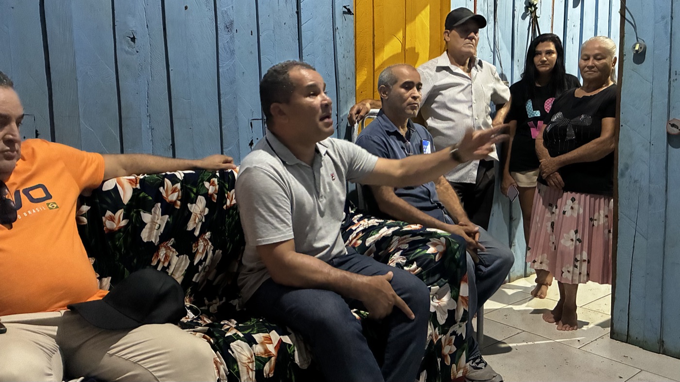 Agleison sentado conversando com uma família